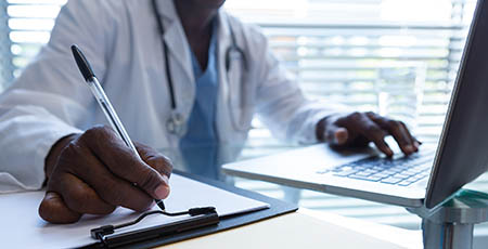 A clinician working at a computer in a hospital.