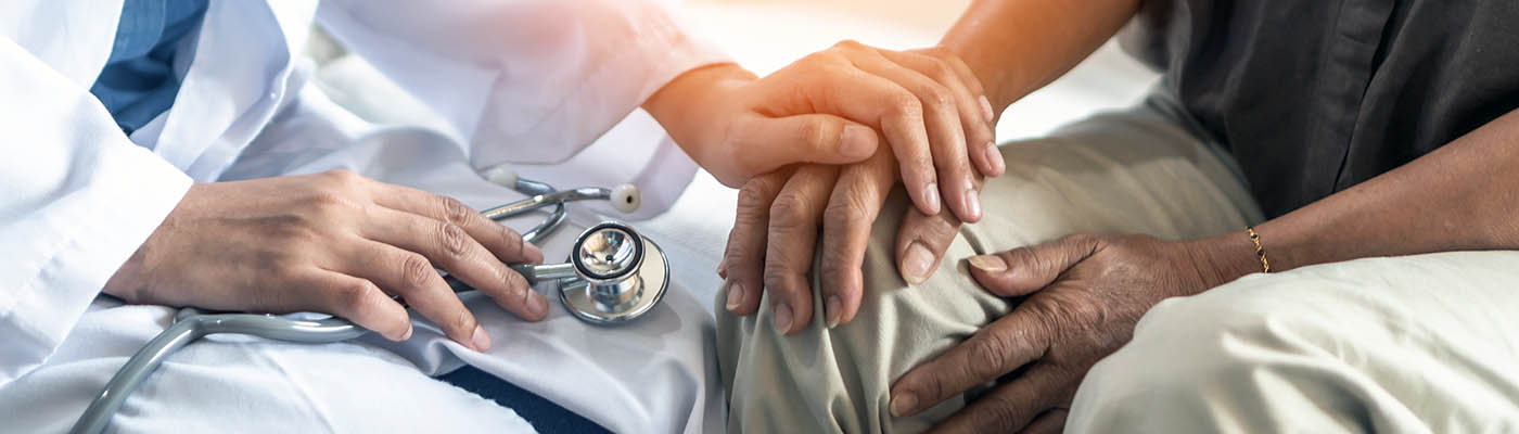 A doctor holds a patient's hand.